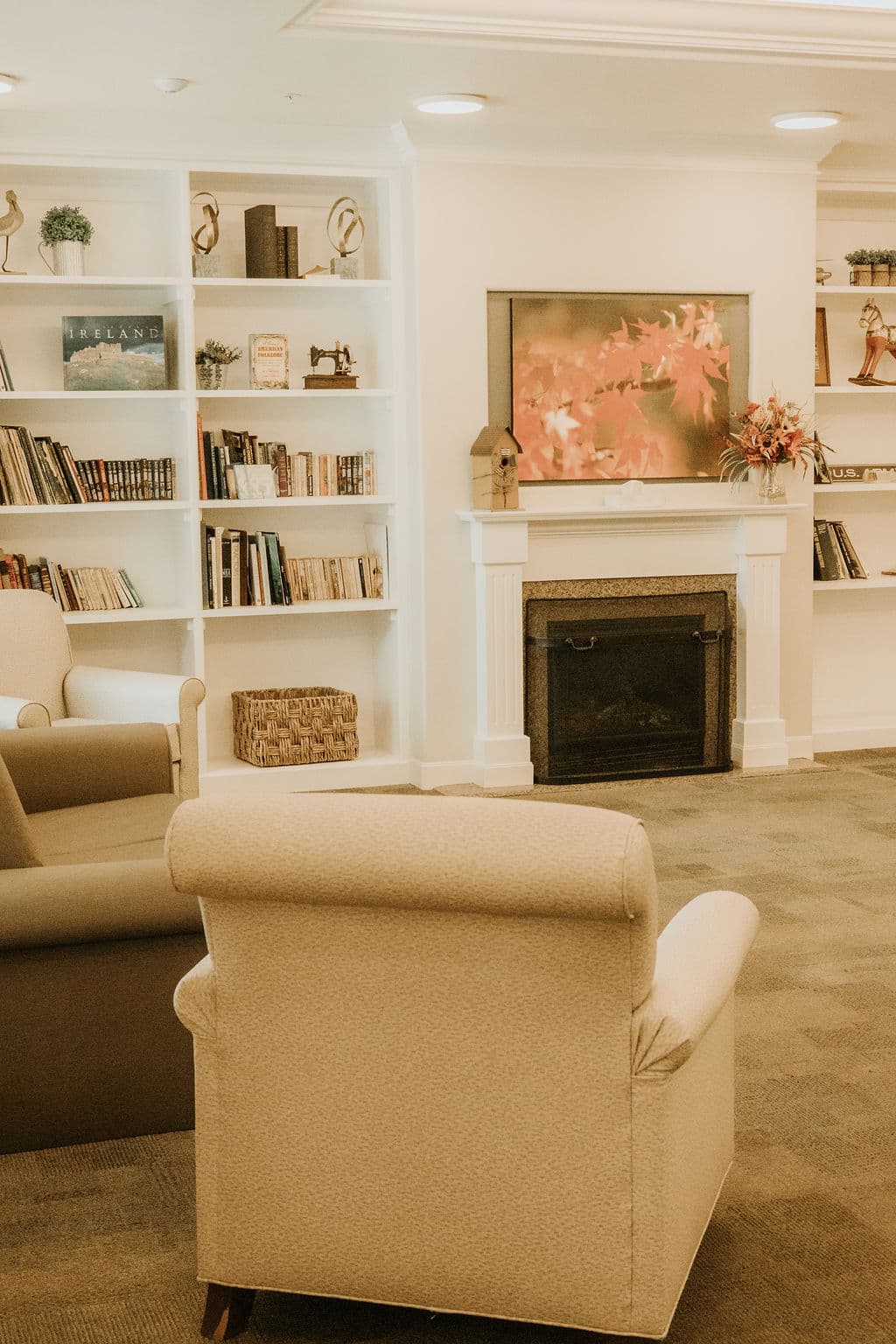 Living room at Oak Grove with armchairs facing a fireplace between built-in bookshelves