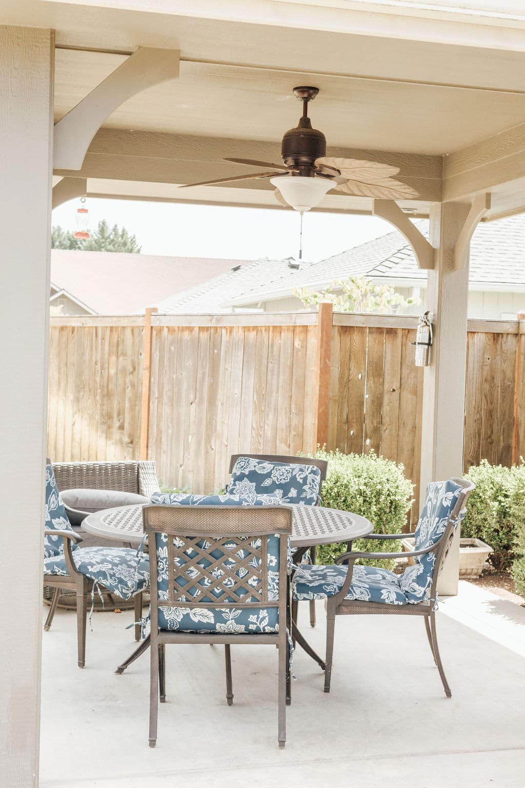 Covered patio at Kinsington Place with a ceiling fan and a cushioned dining set