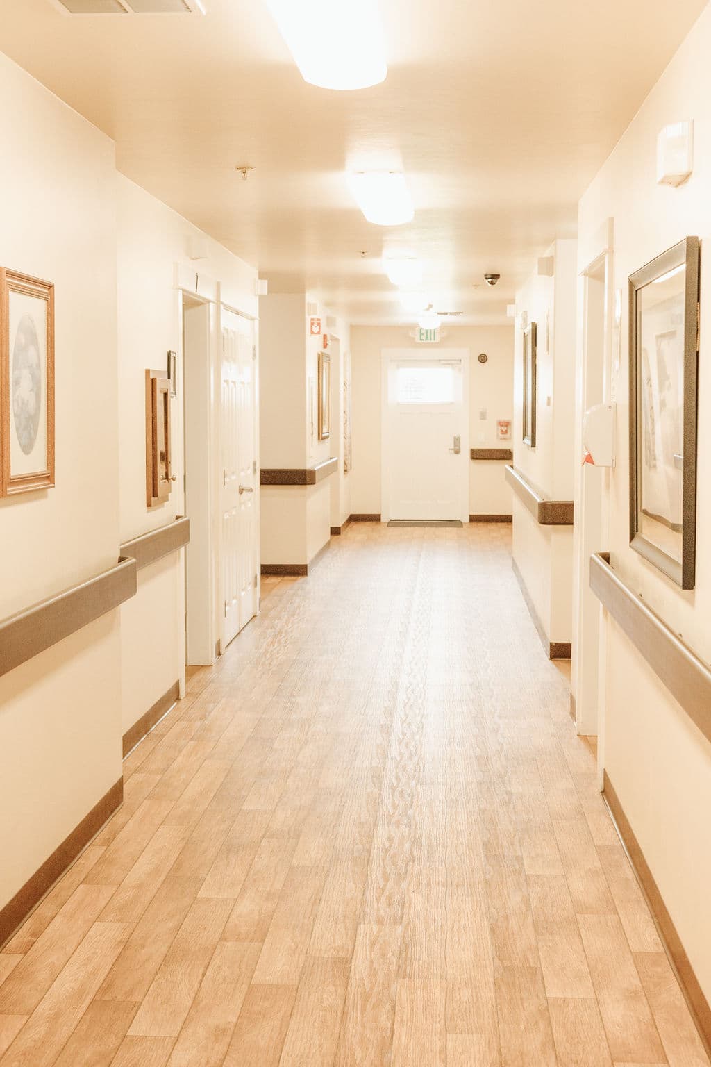 Hallway at Kinsington Place with handrails and framed pictures, leading to the private rooms